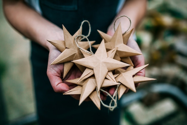 Human holding handmade kraft paper stars in hands