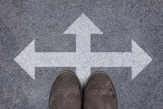 Human legs and directional sign on asphalt road