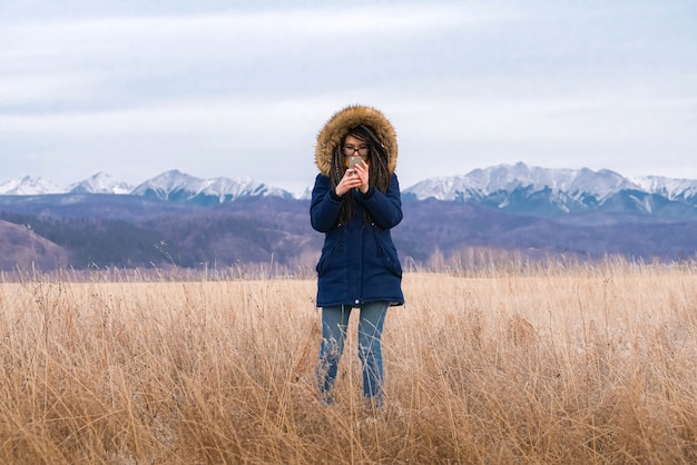 Девушка человека и природы с мобильным телефоном на фоне гор