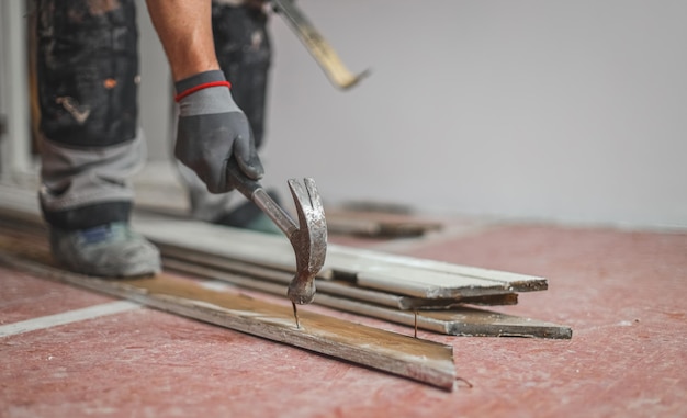 Human pulls out a nail from a board