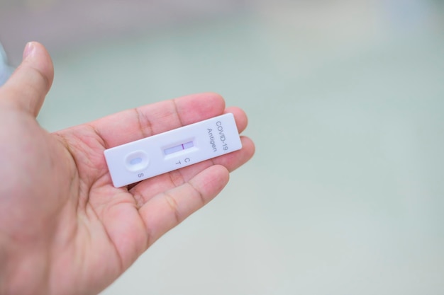 Human's hand holding Negative result shows on rapid test kit for COVID-19