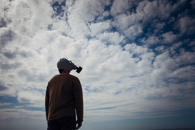 Photo human silhouette in gas mask against moody sky