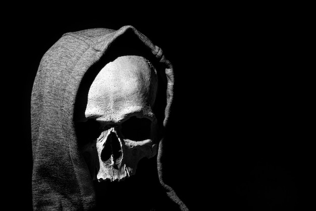 Human skull in hood close up on black background