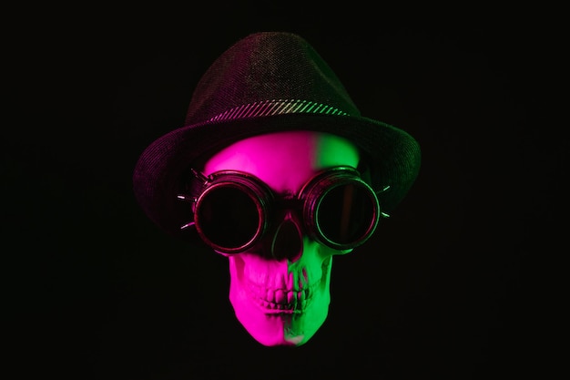 Human skull in steampunk glasses and a hat with a pink green light