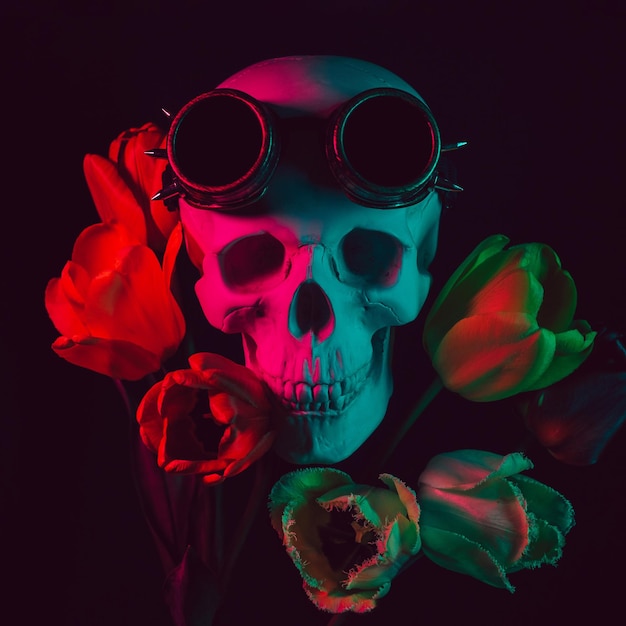 Human skull in steampunk glasses in tulip flowers with colored neon light