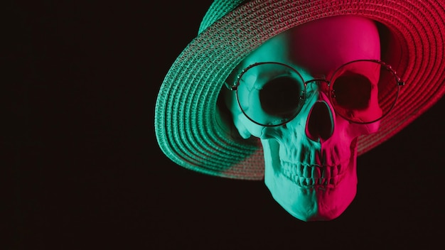 Foto cranio umano con occhiali e un cappello con luce al neon colorata