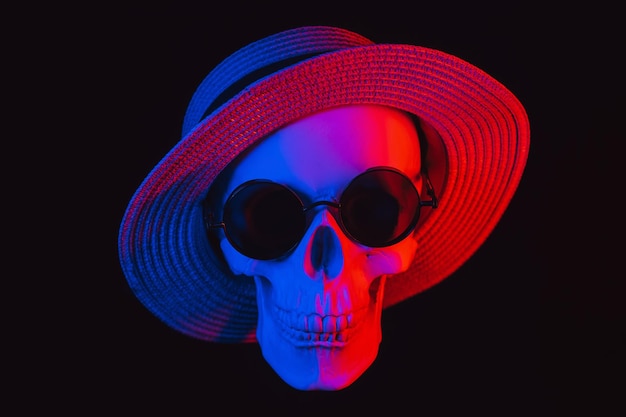 Human skull wearing sunglasses and a hat with colored neon light