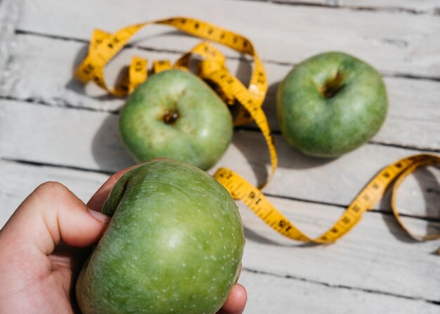 Photo human touches green fresh apples and a yellow centimeter ribbon with the numbers