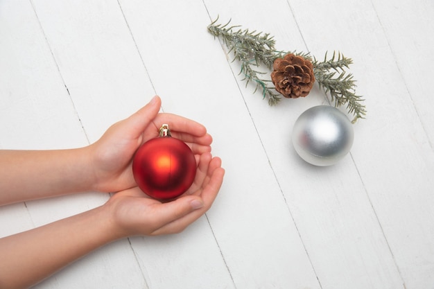 木製の白い背景で隔離のクリスマスボールを持っている人間の手