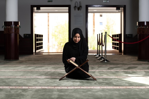 Foto l'umile donna musulmana sta pregando con il corano
