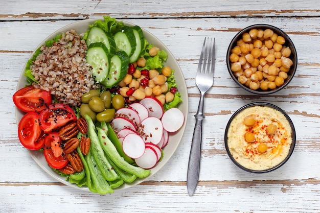 Hummus in bowl, vegetables sticks, chickpeas, olives. 