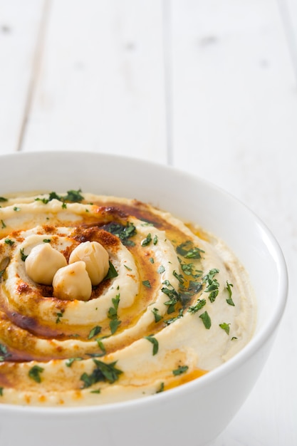 Hummus in bowl on white wooden table copy space