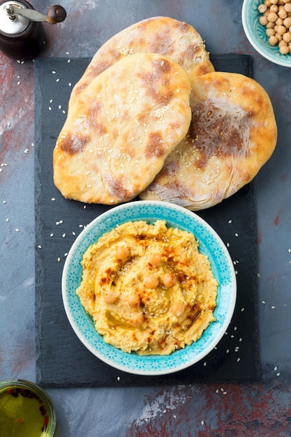 Hummus chickpeas with spices and pita flat cake in a plate on a background of gray stone Selective focus