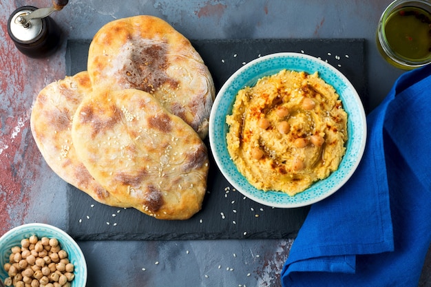 Hummus, chickpeas, with spices and pita, flat cake in a plate on a surface of gray stone