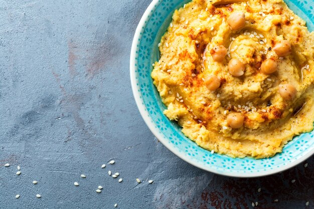 Hummus, chickpeas, with spices and pita, flat cake in a plate on a surface of gray stone