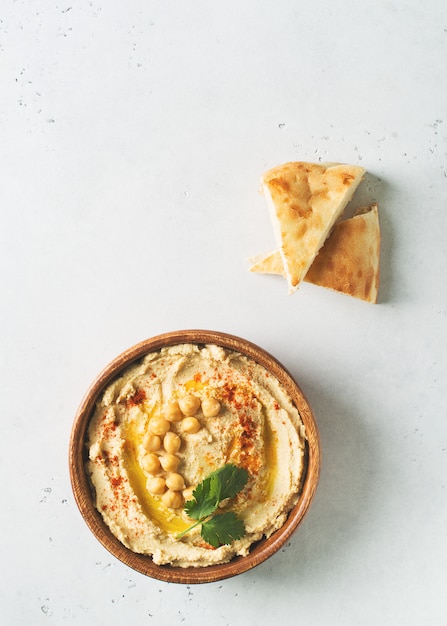 Hummus dip with chickpea, pita  and parsley in wooden plate on white background 