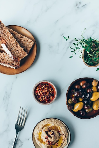 Hummus gemengde olijven en zuurdesem brood op een marmeren achtergrond