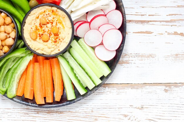 Hummus in kom, groentensticks, kikkererwten, olijven.