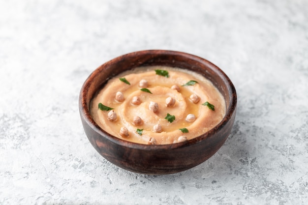 Hummus into a brown wooden plate. 