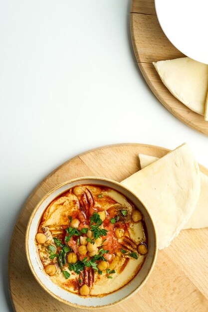 Hummus met pita-kikkererwten en tomaten in een kom op een houten plank