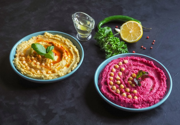 Hummus met rode biet en traditionele hummus op een zwarte keukentafel