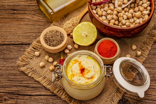 Hummus on old wooden table. Dry chickpea, olive oil, lemon, cumin and chili pepper