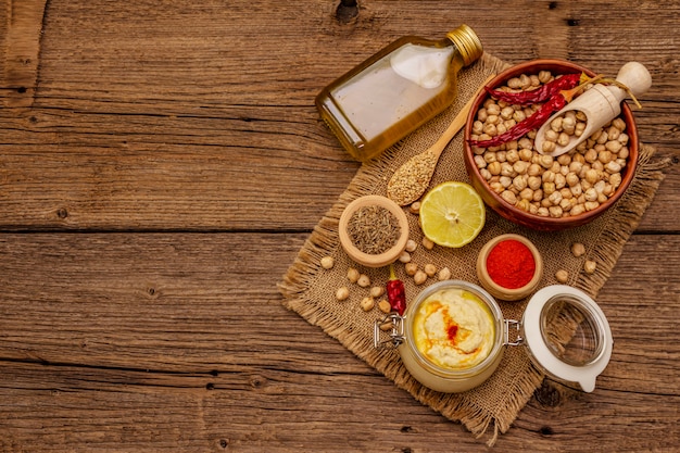 Hummus on old wooden table. Dry chickpea, olive oil, lemon, cumin and chili pepper