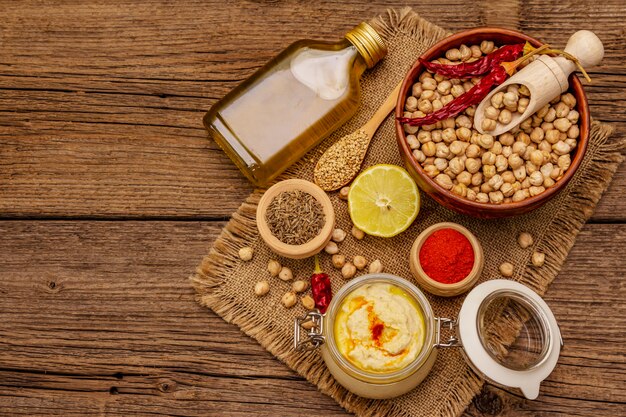 Hummus on old wooden table. Dry chickpea, olive oil, lemon, cumin and chili pepper