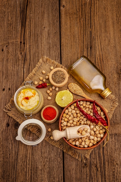 Hummus on old wooden table. Dry chickpea, olive oil, lemon, cumin and chili pepper