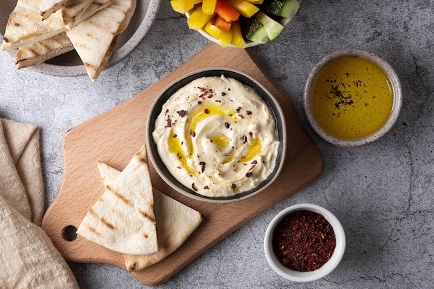 Hummus seasoned with olive oil with pita bread on cutting board on a gray background vegetable dip