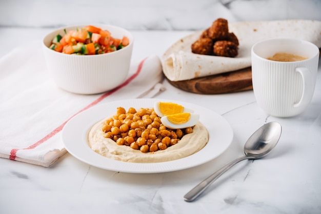 Hummus with boiled chickpeas, egg, falafel, lavash and salad and coffee. Breakfast. Middle Eastern dish