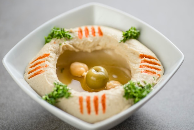 ひよこ豆とオリーブのフムスは、アラビア料理の灰色の背景の平面図に分離された皿で提供しています