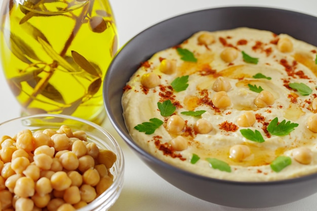 Hummus with chickpeas and olive oil in a dark bowl selective focus