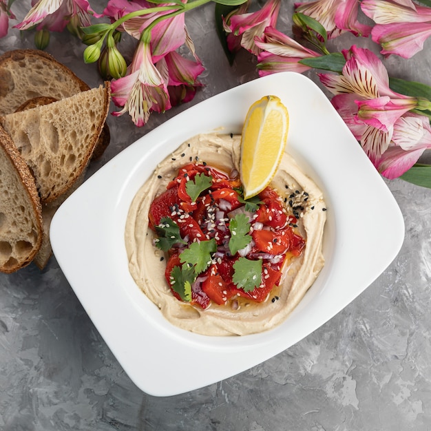 Hummus with a slice of lemon on a white plate