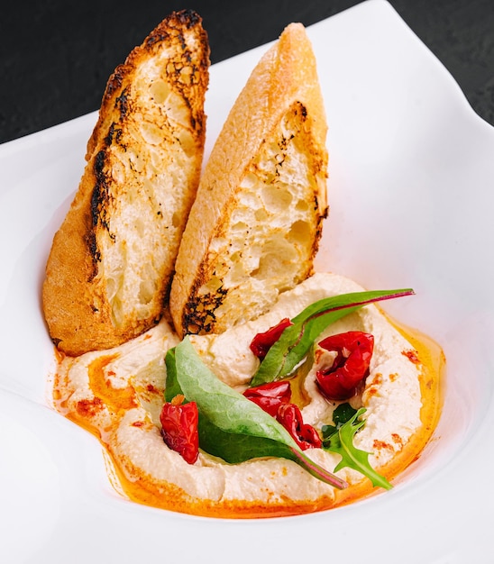 Hummus with toasted baguette croutons on plate