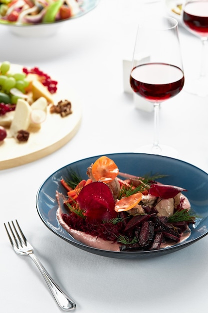 hummus with vegetables, beetroot hummus with fried vegetable sticks and svela leaves, with a glass of wine on the festive table.