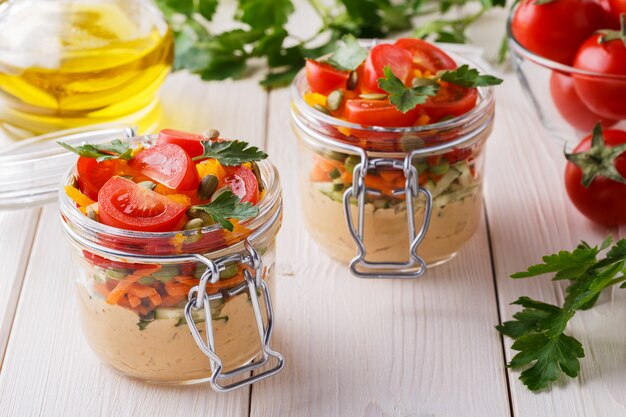 Hummus with vegetables in glass jars