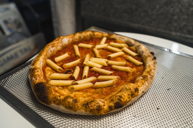 Foto humoristisch italiaans voedselconcept bereidt pizza met penne macaroni en mengt traditionele italiaanse gerechten