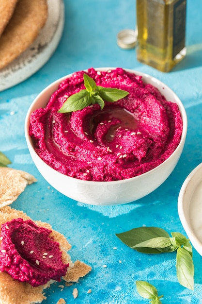 Humus schaal. Rode bietenhummus met verse groenten, olijfolie op tafel