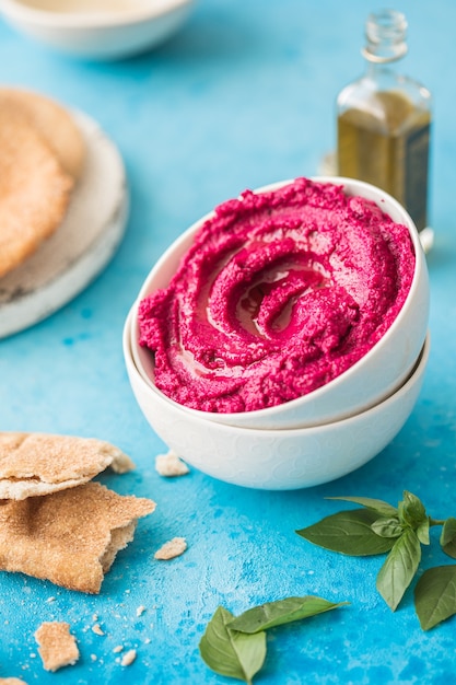 Humus schaal. Rode bietenhummus met verse groenten, olijfolie op tafel