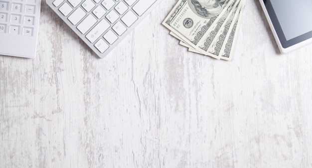 Photo hundred dollar banknotes with a computer keyboard, tablet and calculator.