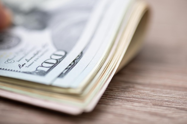 Hundred dollar banknotes on wooden table close up