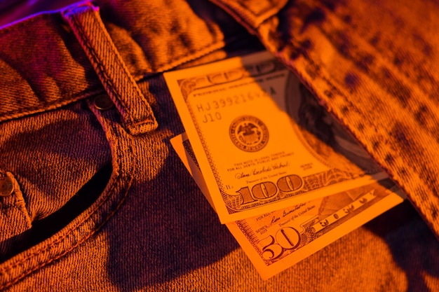 Hundred dollar bill in pocket of blue jeans toned Dollars in neon light Banknotes