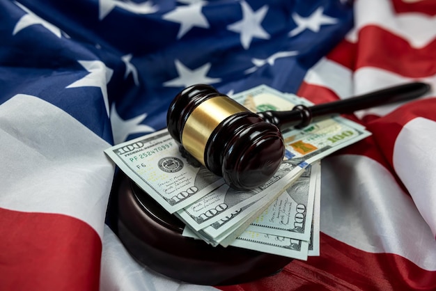 Hundred dollar bills and a judge's gavel placed on an american flag