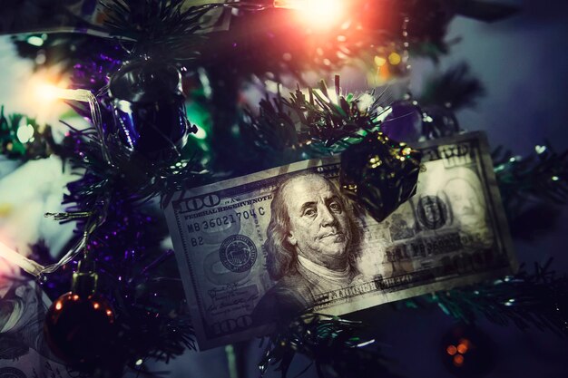 Hundred dollar bills. Money on Christmas tree. Small decorated Christmas tree on a blue background.