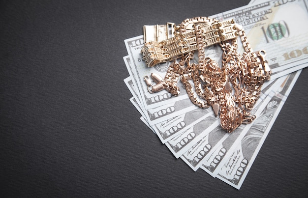 Hundred dollars with a gold jewelry on black wall