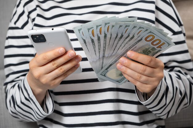 Hundreddollar bills and a smartphone in the hands of a person