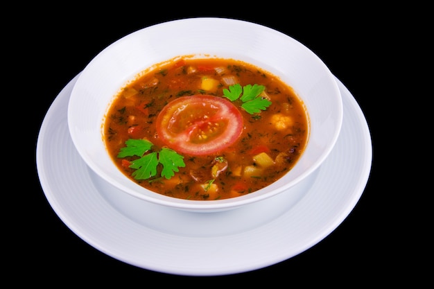 Hungarian goulash - thick vegetable soup with beef and tomatoes on white boul.