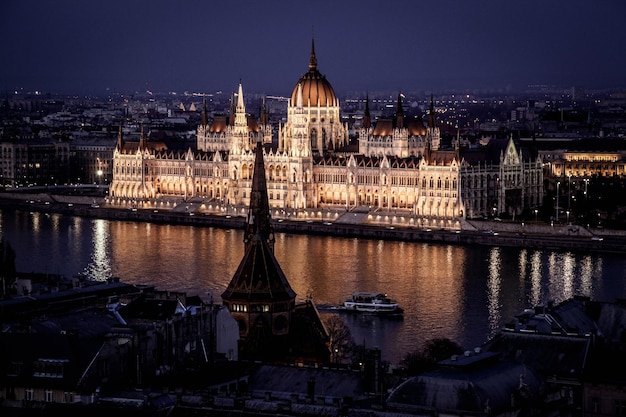 写真 ハンガリーの議会の建物は夜に市内で川のそばにあります