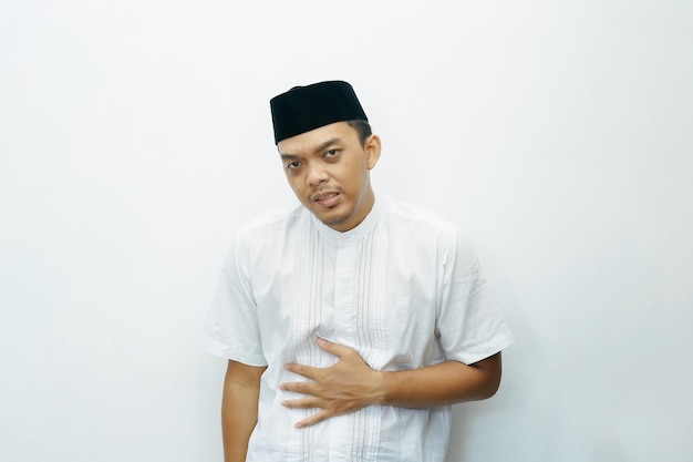 Photo hungry asian indonesian muslim man placing his hands on stomach for stomach ache gesture